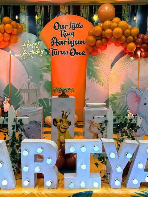Jungle king first birthday stage with orange balloons and animal cut-outs