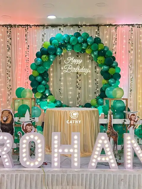 Safari themed first birthday stage with a green balloon ring and animal props